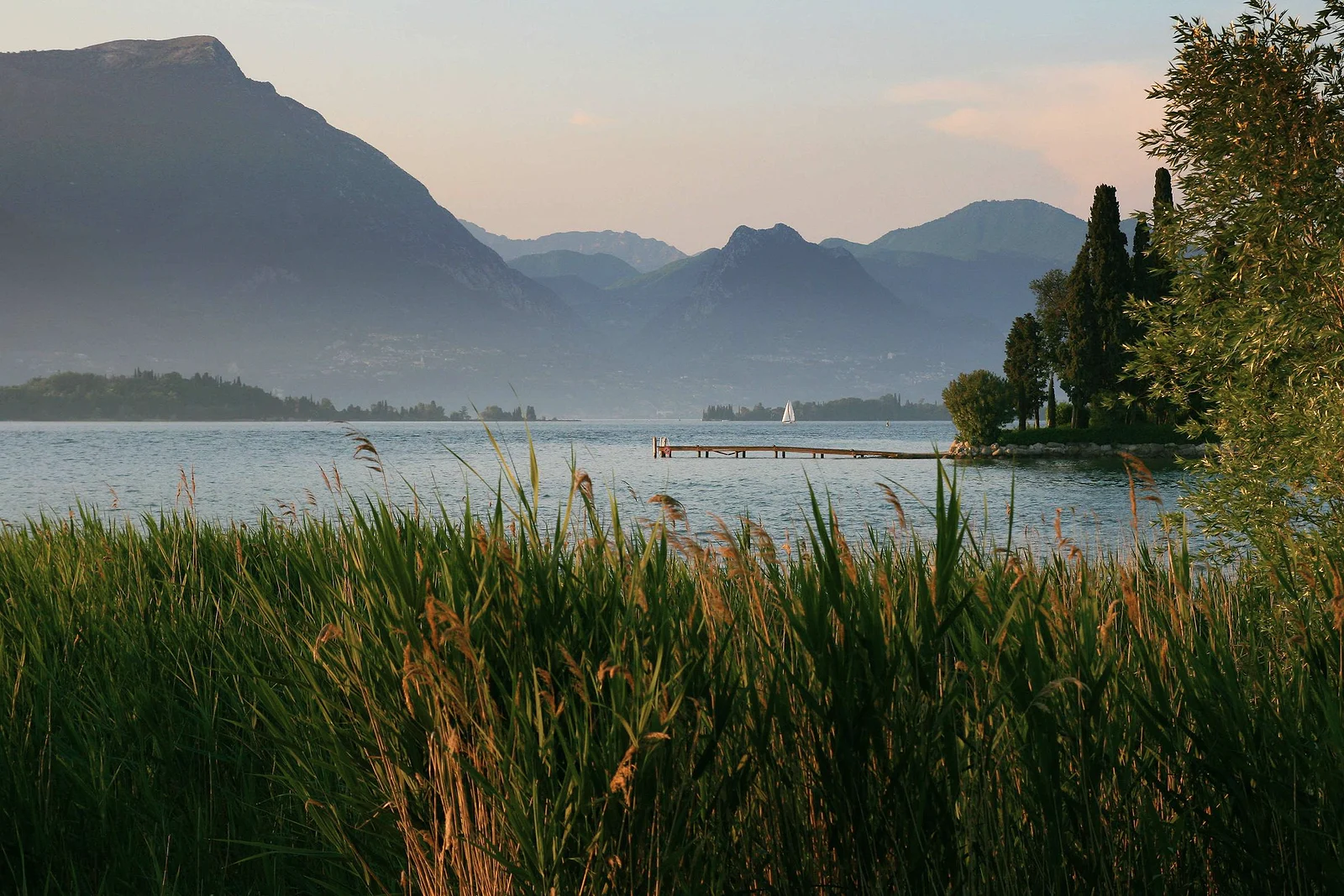 A still lake at dusk with mountains behind